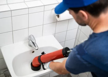 Plumber Cleaning Drain And Bathroom Sink Using Pump